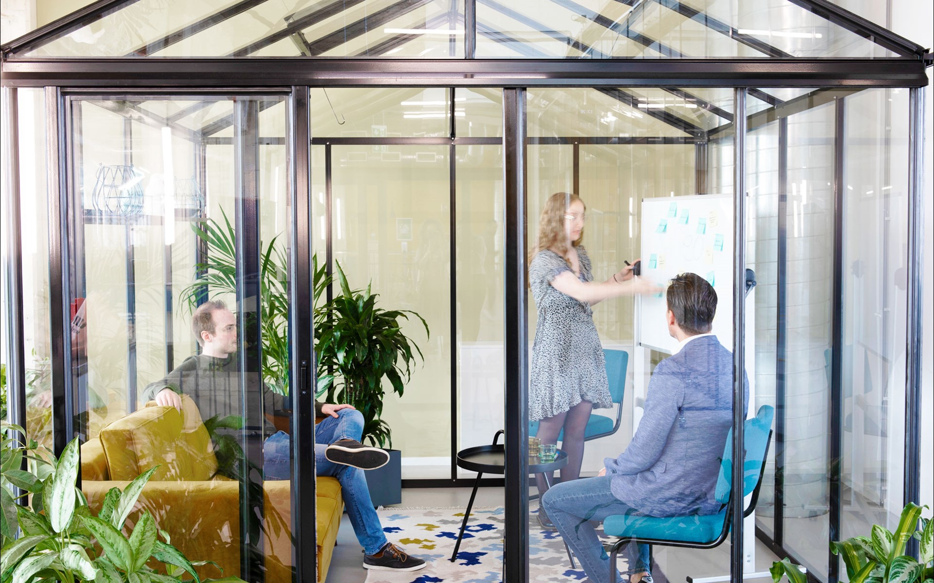 een groep mensen die in een kamer met glazen wanden zit
